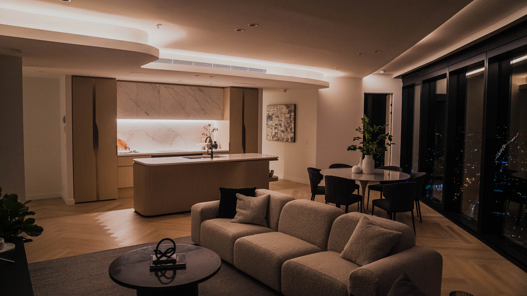 Open-plan living room with warm cove lighting at dusk